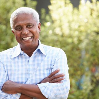 Older man, with arms crossed, smiling