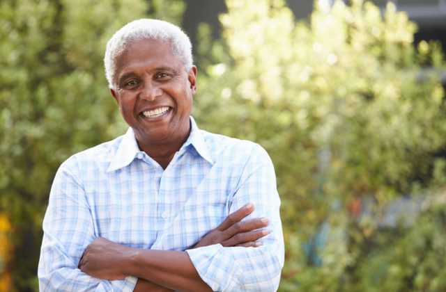 Older man, with arms crossed, smiling