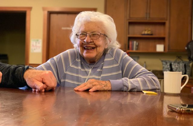 Older person sat at table smiling