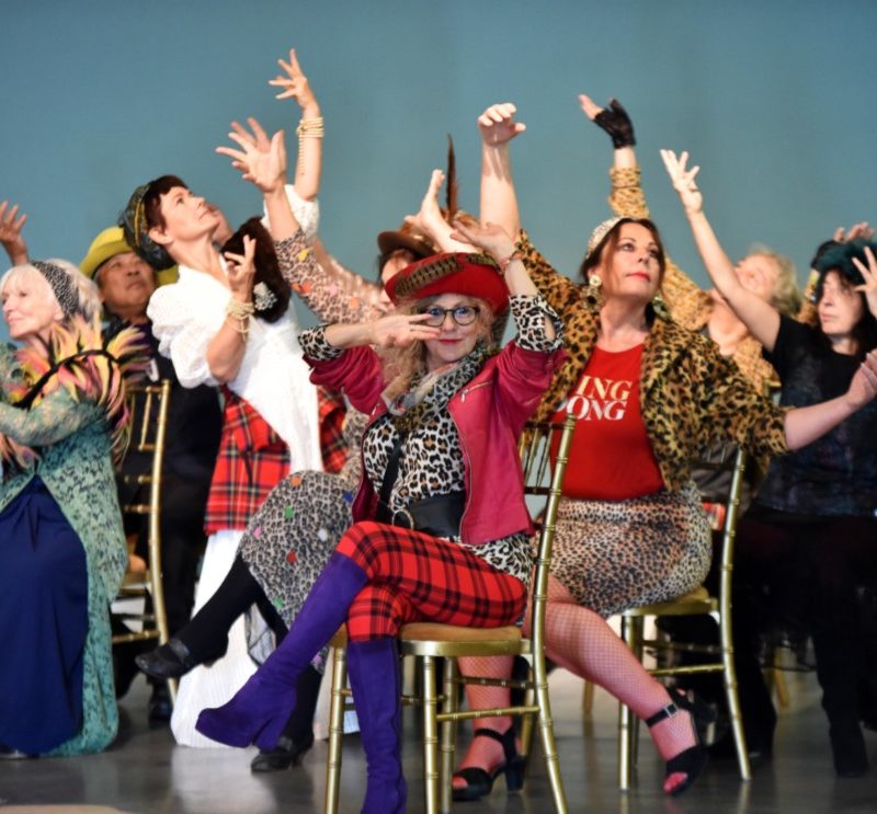 Group of brightly dressed older people holding a dance pose together