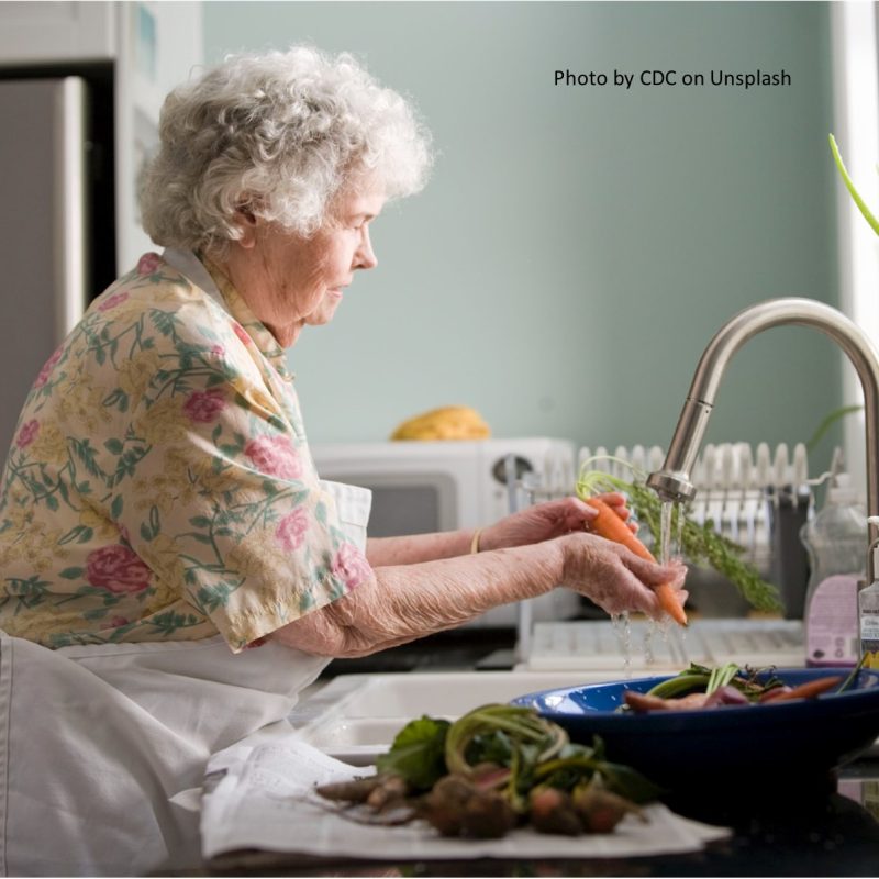 Older woman in kitchen washing carrots