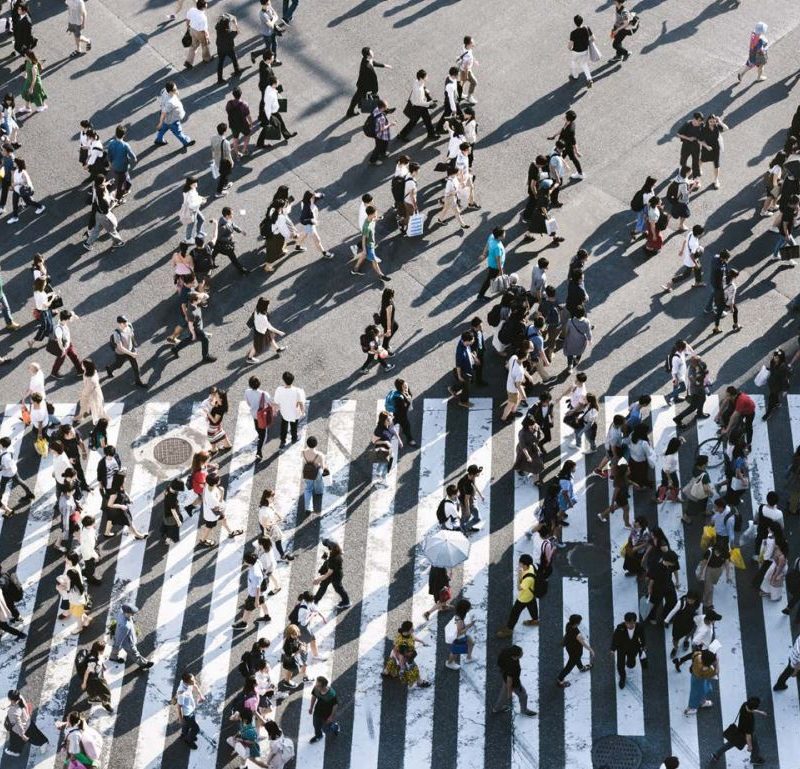 Lots of people, viewed from above, crossing main roads in an urban environment