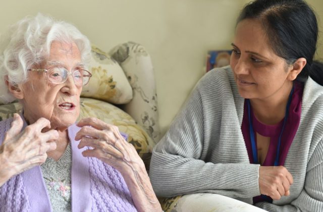 Older woman talking, with younger woman, leaning close, listening