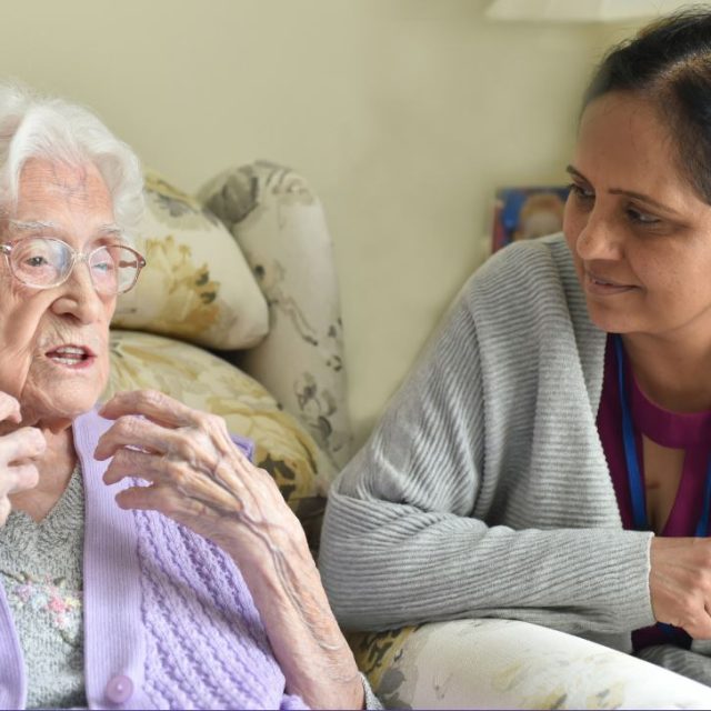 Older woman talking, with younger woman, leaning close, listening
