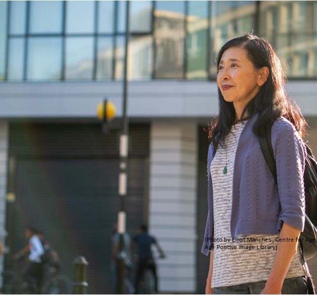 Older woman walking past a building