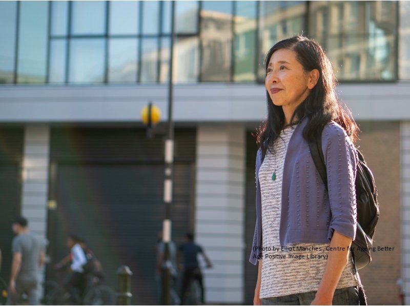 Older woman walking past a building