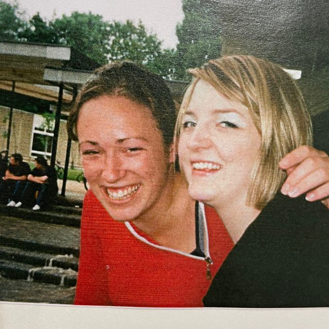 Two women sat very close together, both smiling