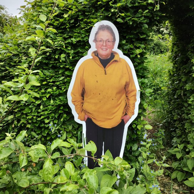 Photo of Jessica, seemingly 'cut out' against a background of green trees and shrubs