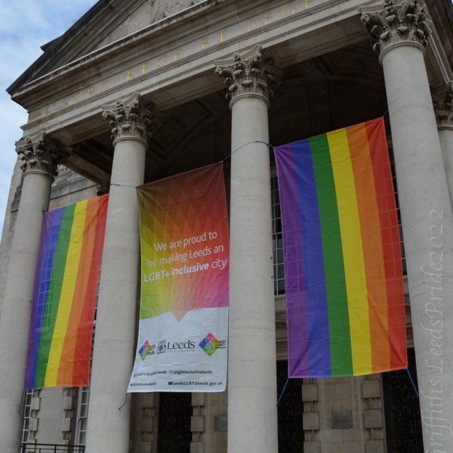 A white building with steps and columns (Leeds Civic Hall) bedecked with rainbow flags