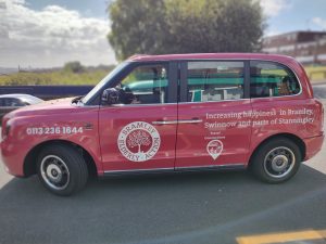 Red cab, with logos of Bramley Elderly Action and Travel Connections on the side.