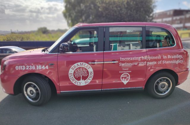 Red cab, wit logos of Bramley Elderly Action and Travel Connections on the side.