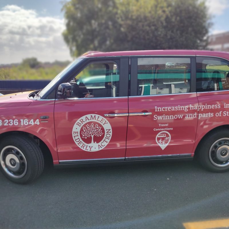 Red cab, wit logos of Braamley Elderly Action and Travel Connections on the side.