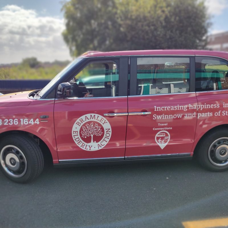 Red cab, wit logos of Bramley Elderly Action and Travel Connections on the side.